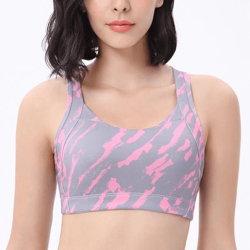 Woman wearing stylish pink and gray elastic sports bra with cross back for comfortable workouts.